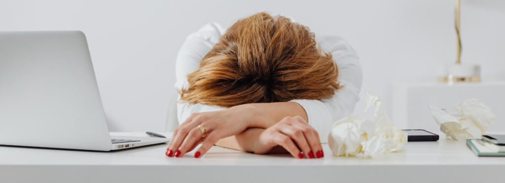 imagem de uma mulher com o rosto sobre as mãos, indicando cansaço e assédio moral